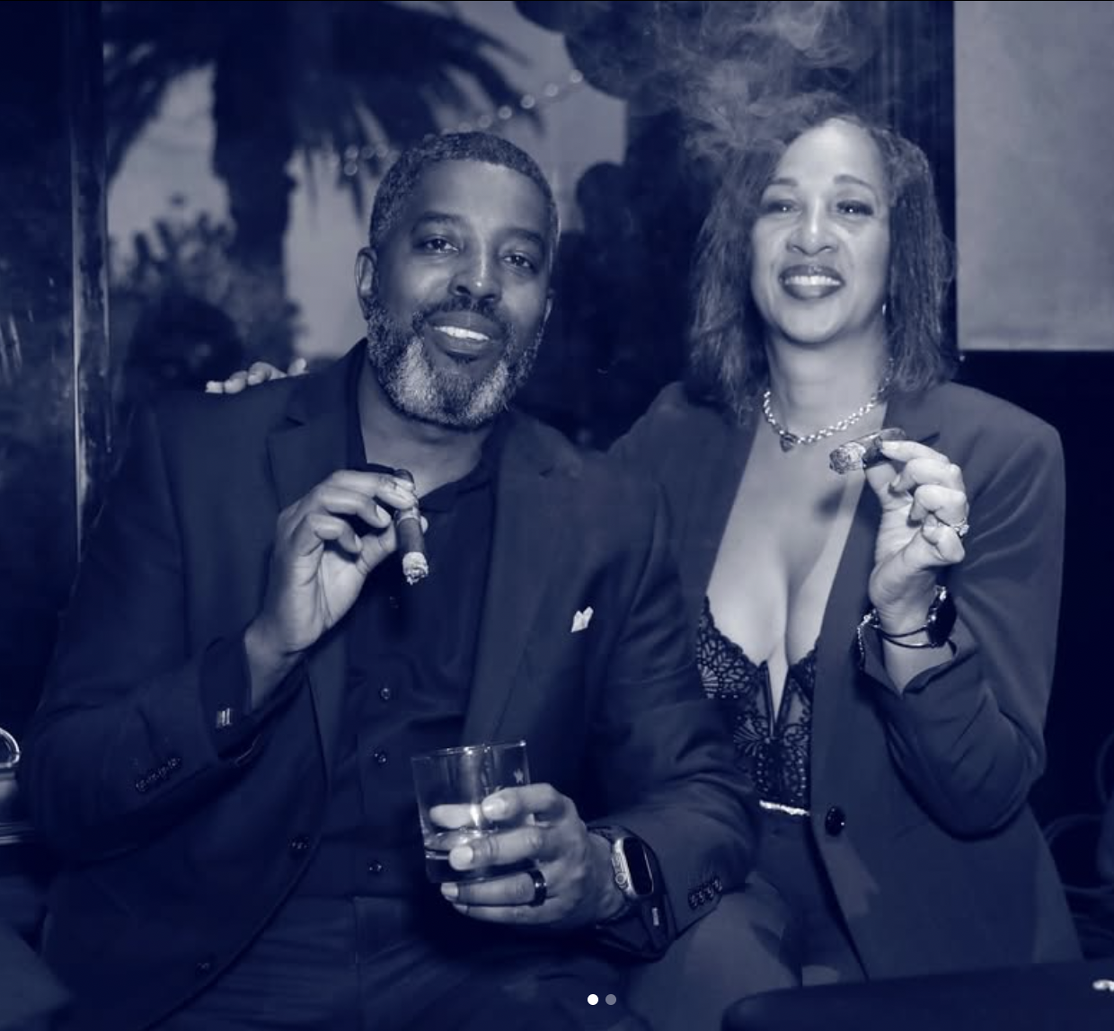 Nancy and Lyman sitting together, smiling, both enjoying cigars.