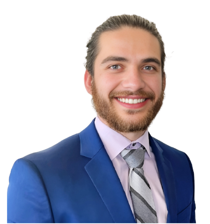 A smiling man with a beard and light brown hair, wearing a blue suit, light purple dress shirt, and a gray striped tie.