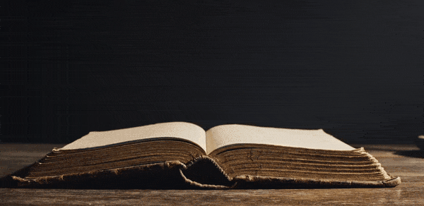 Libro abierto y viejo sobre una mesa de madera con fondo oscuro