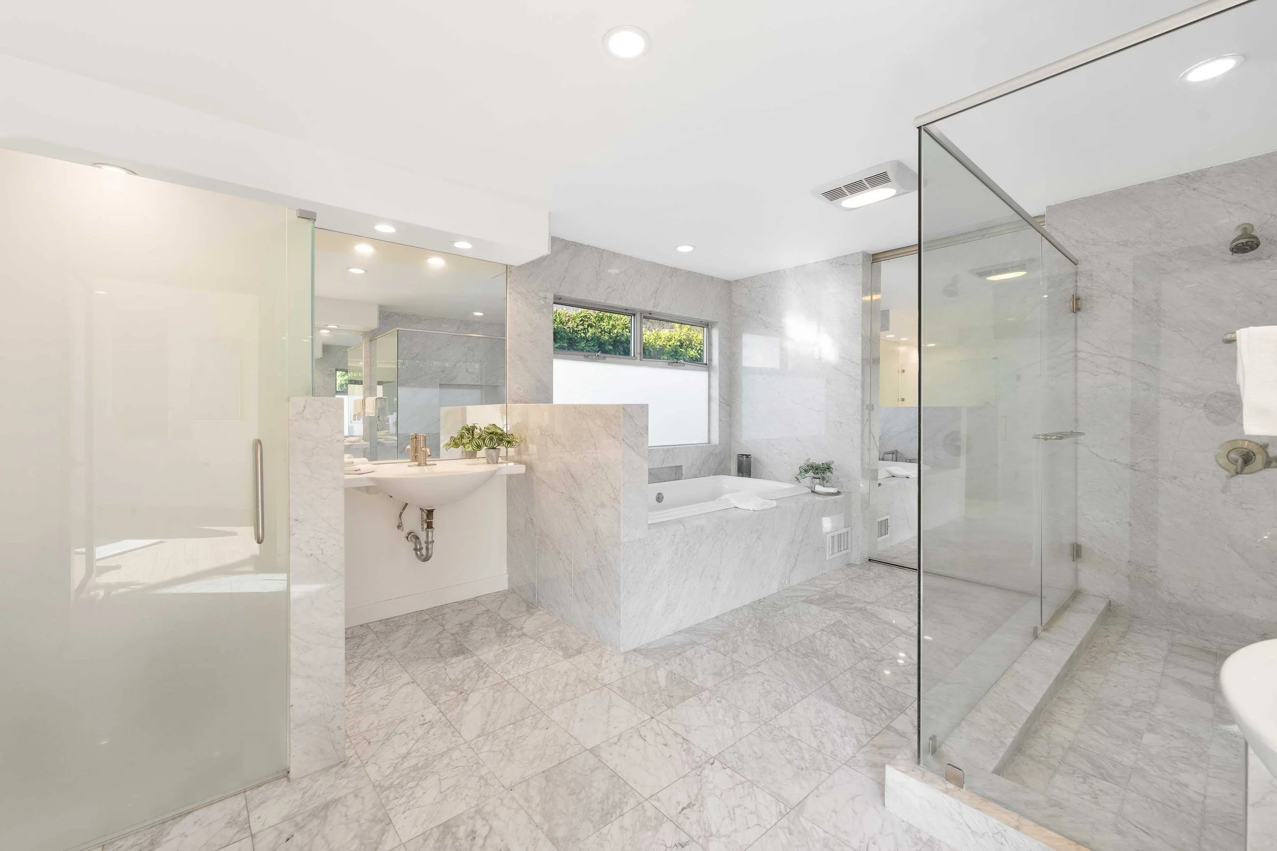 Modern marble bathroom with a shower, bathtub, and vanity with a mirror.