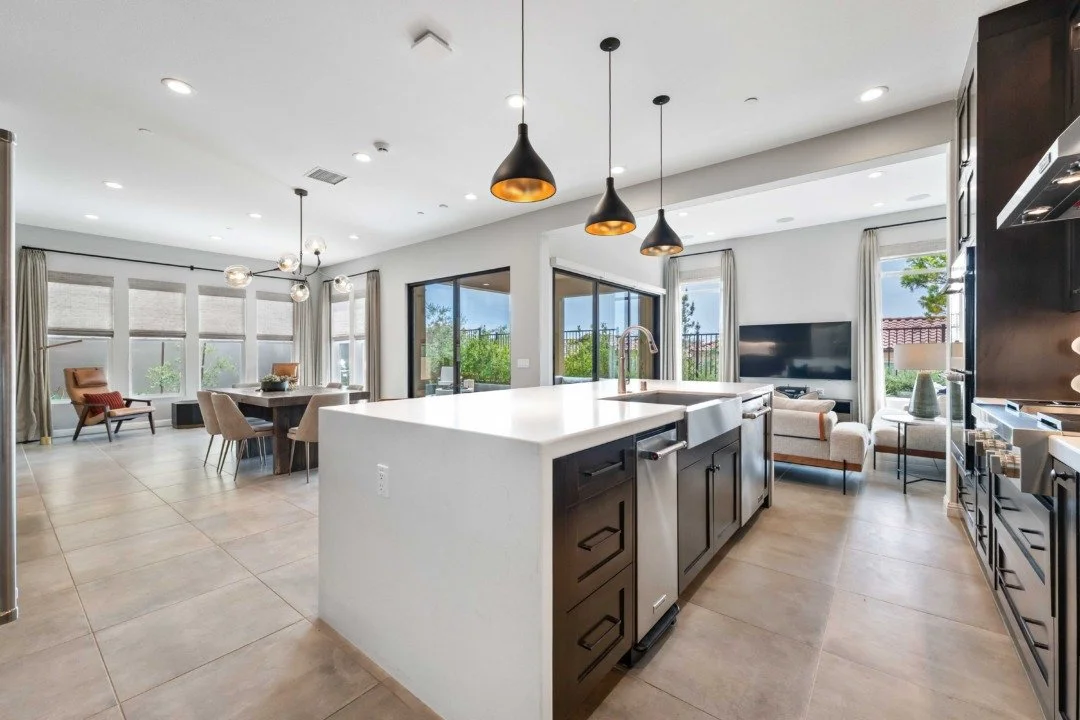 Open-concept living room and kitchen with modern decor, large windows, and outdoor view.