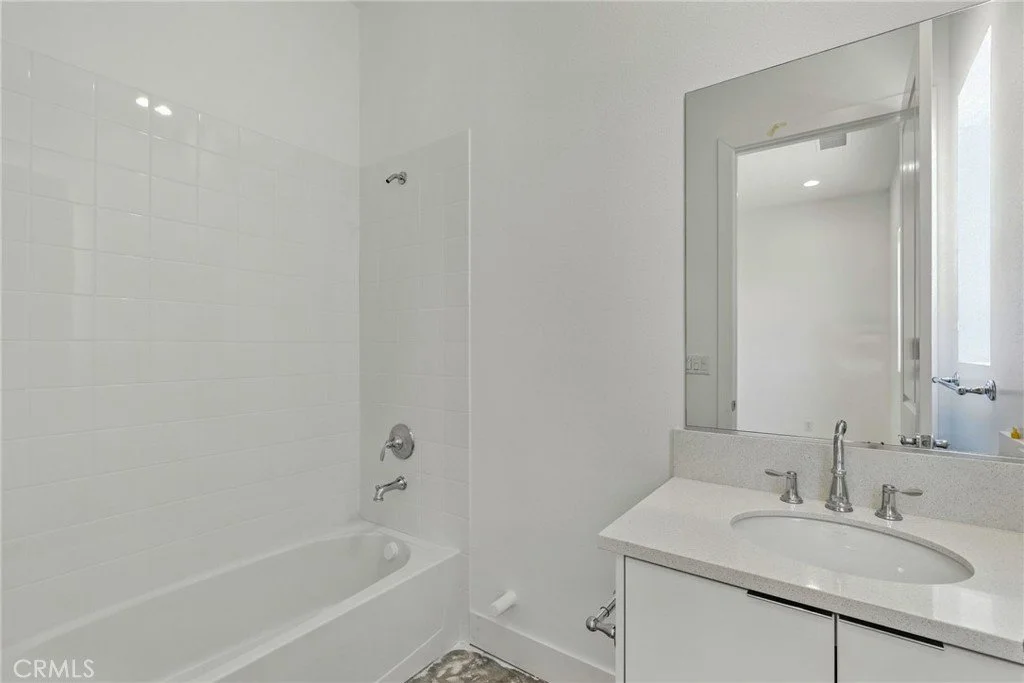 Bathroom with bathtub, shower, and vanity with mirror.