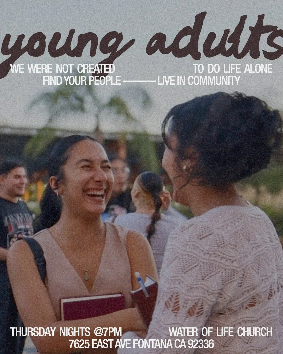 Two women are laughing and talking outdoors at a church event, with other people in the background. Text overlay promotes a young adults church group meeting Thursdays at 7pm at Water of Life Church, 7625 East Ave, Fontana, CA 92336.
