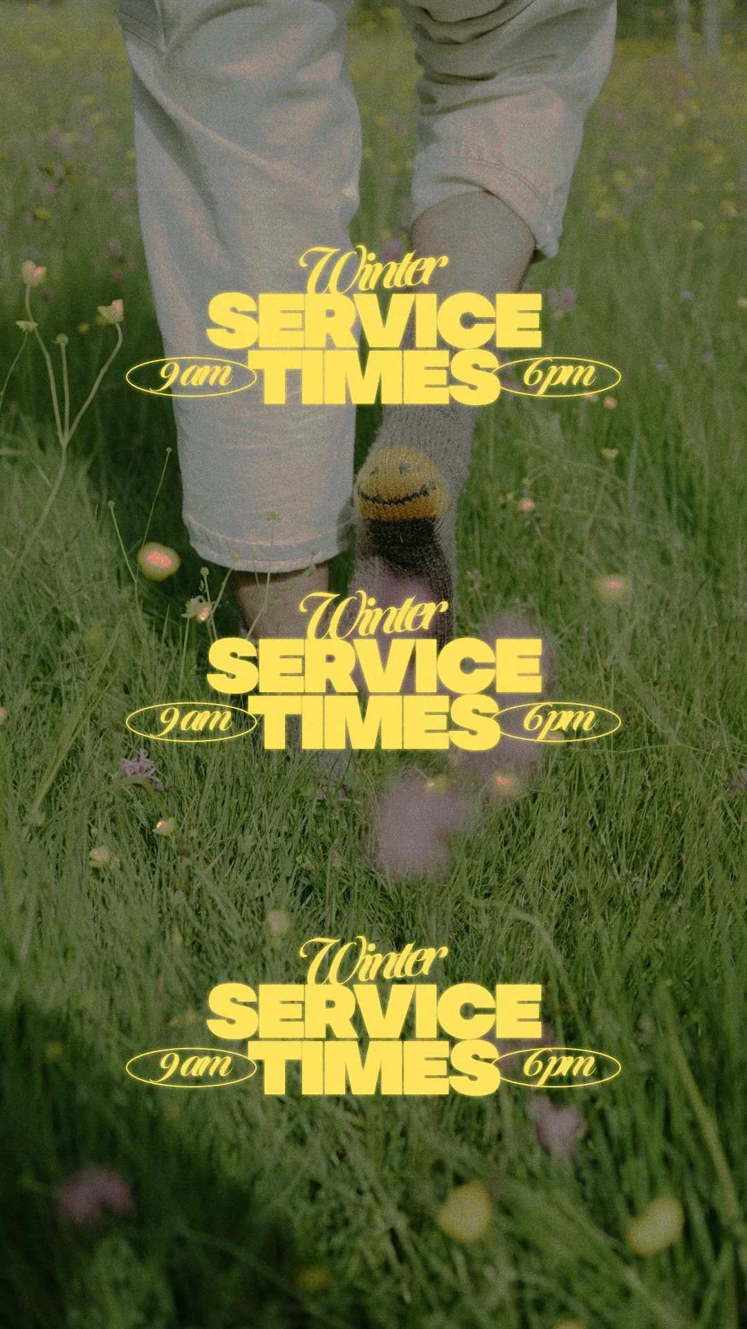 A person walking on grass, wearing white pants, grey sock, and smiling sock with a smiley face.