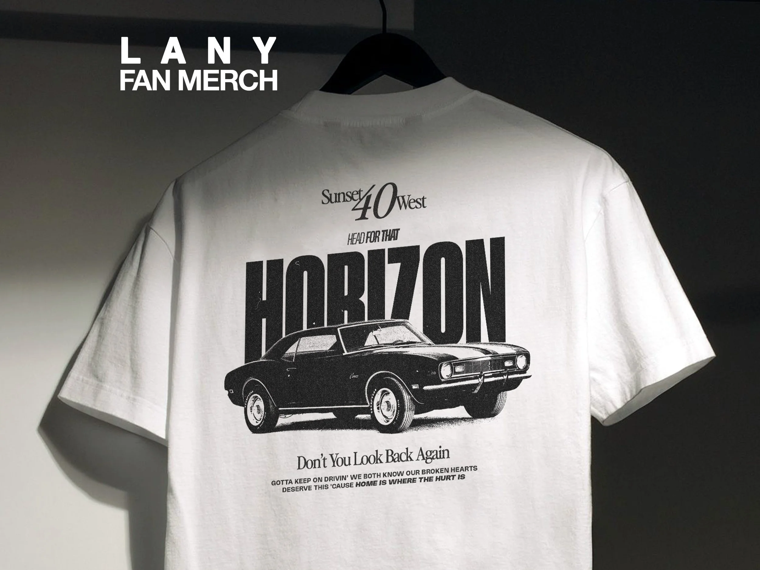 White T-shirt hanging on a black hanger with black text and an illustration of a black vintage car.