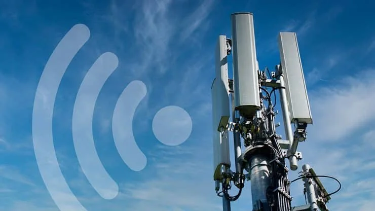 Cell tower with antennas against a blue sky with scattered clouds.