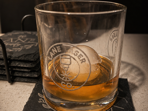 Custom laser-engraved whiskey glass featuring the Lane Laser Co. logo.