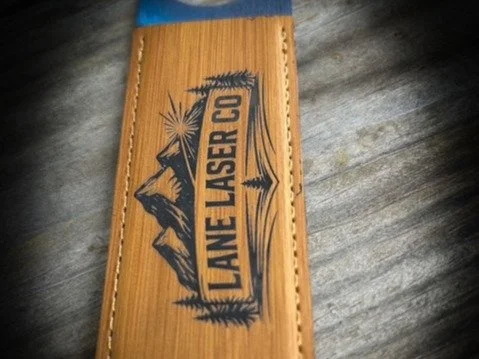 Laser-engraved wood featuring a custom Lane Laser Co. mountain and pine tree design.
