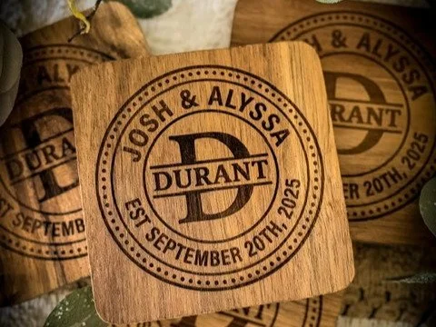 Personalized wood coaster with custom wedding monogram, names, and date laser engraved into the wood.