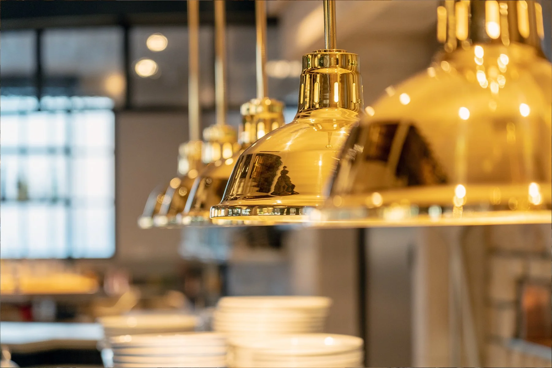 Close-up of shiny, gold pendant lamps hanging in a modern restaurant.