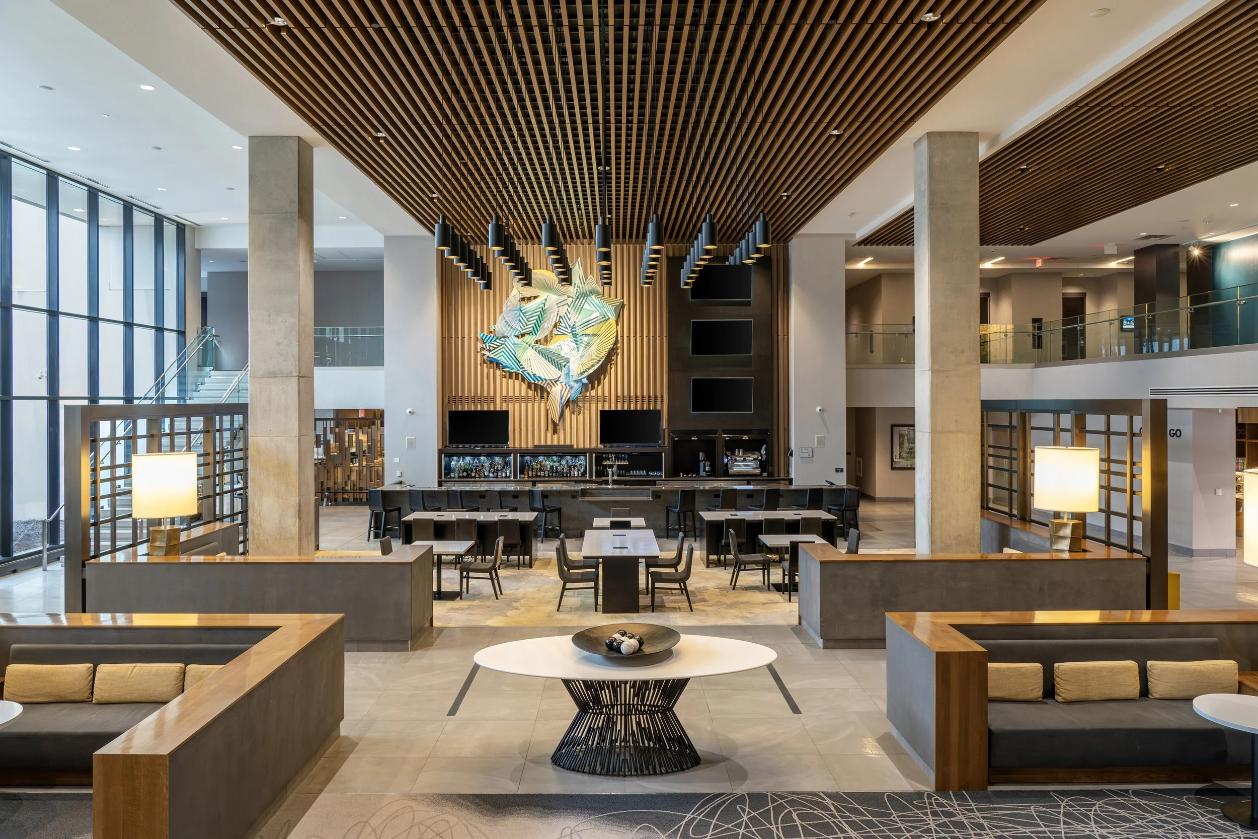 Modern hotel lobby with seating area, bar, and decorative wall art.