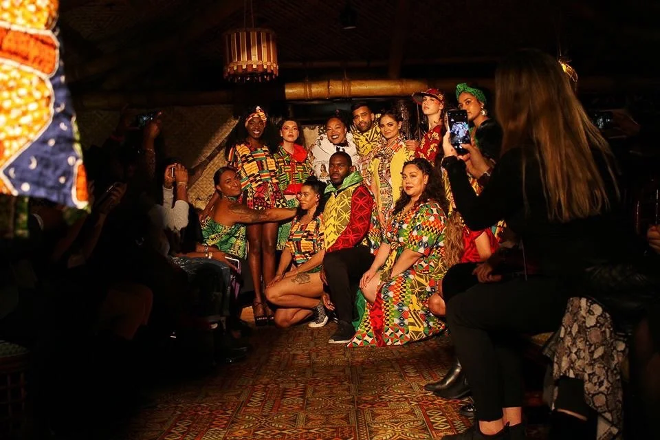 A group of models wearing colorful garments gather for a photograph