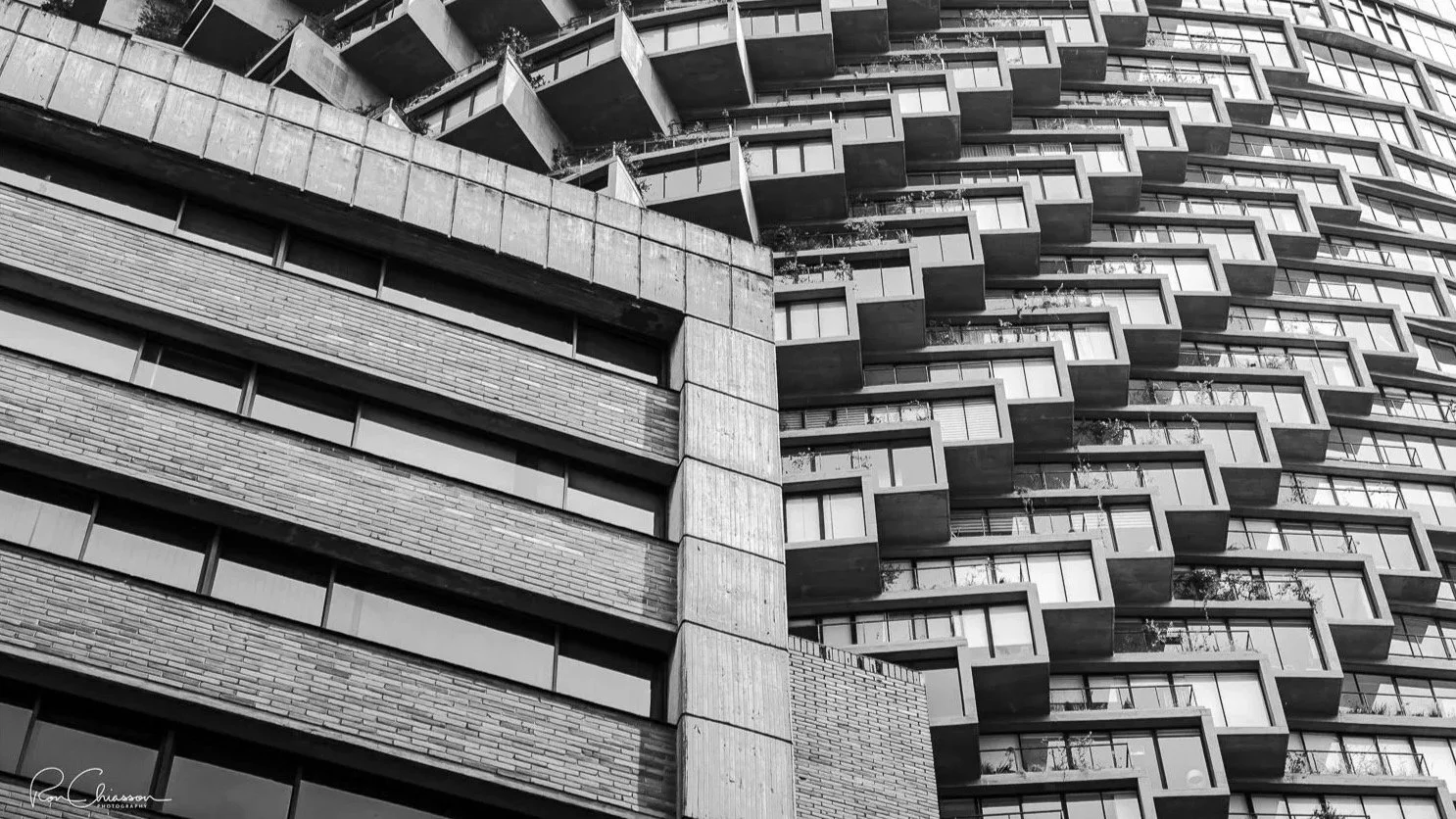 The curves of the Iqon building behind the straight lines of a neighbouring building. ©Ron Chiasson Photography @rsonphoto.