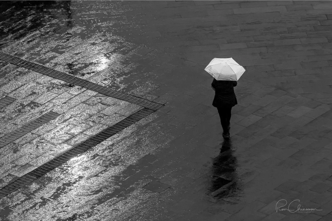 Another rainy day in Quito. A lady dressed in dark clothing is sharply contrasted to the white umbrella she is holding. ©Ron Chiasson Photography @rsonphoto.