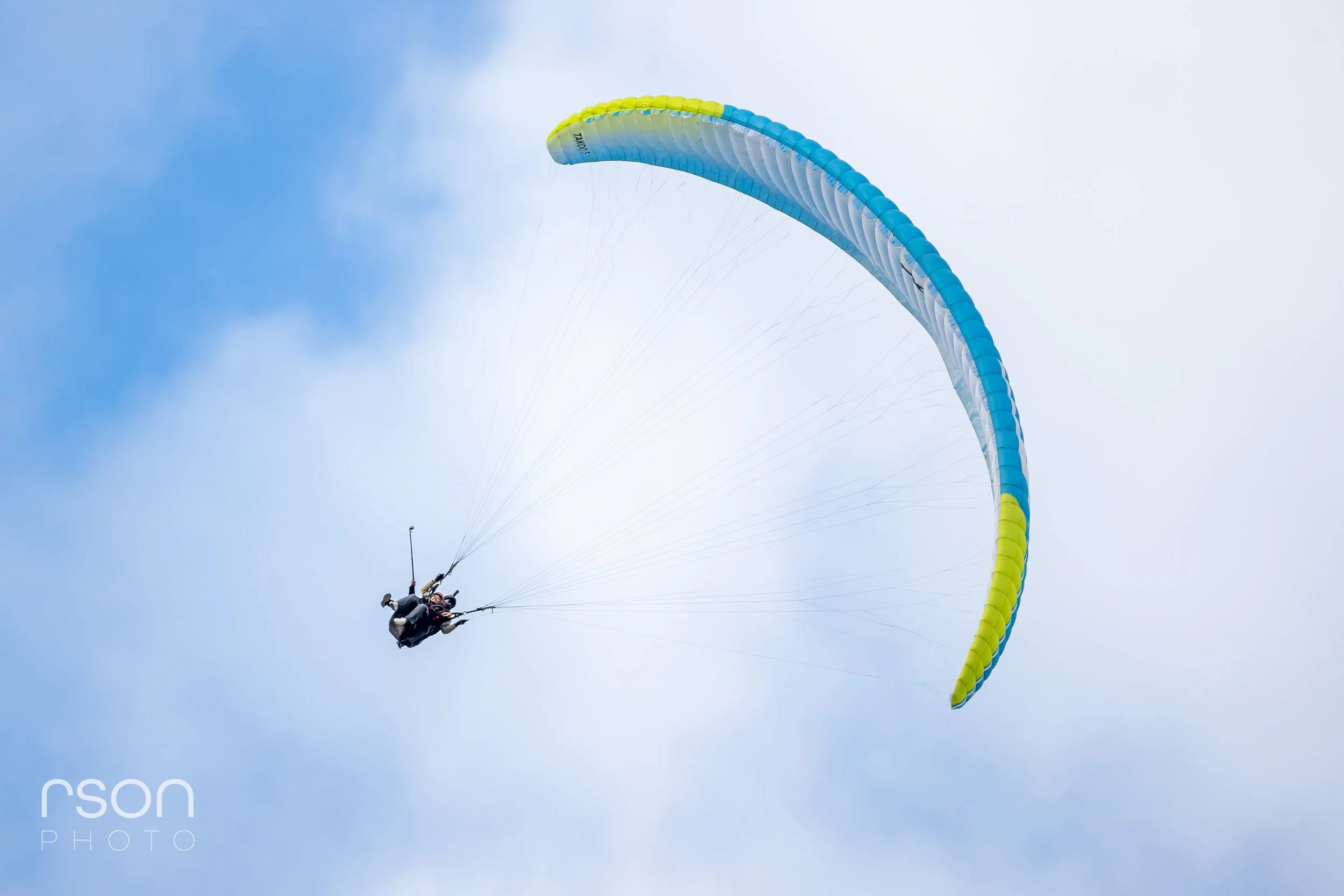 Paraglider flying in blue sky with some clouds.