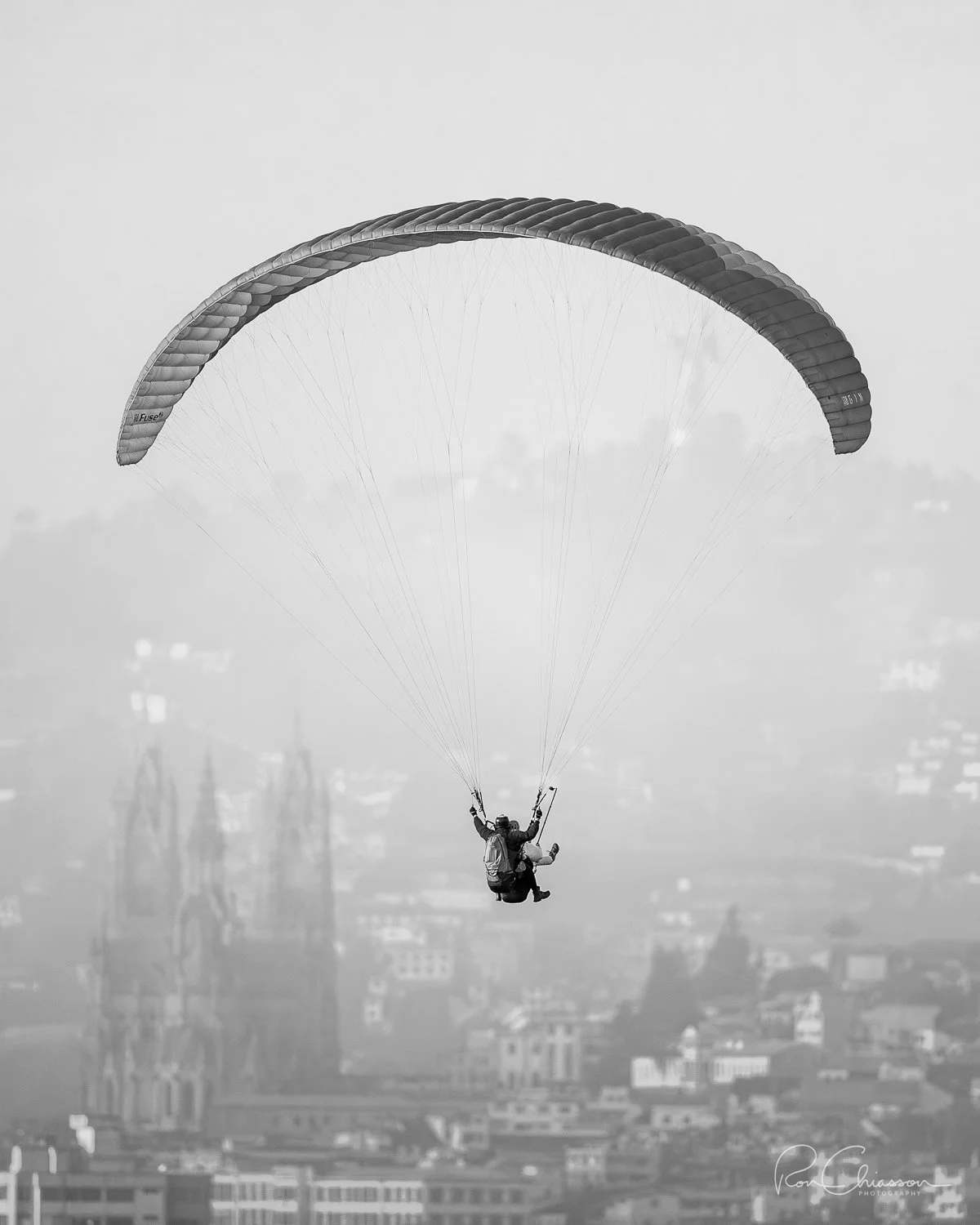 A Paraglider descends from Cruz Loma. The Basilica de Voto National and the Virgin of Quito are under the wings of the paraglider. ©Ron Chiasson Photography @rsonphoto.
