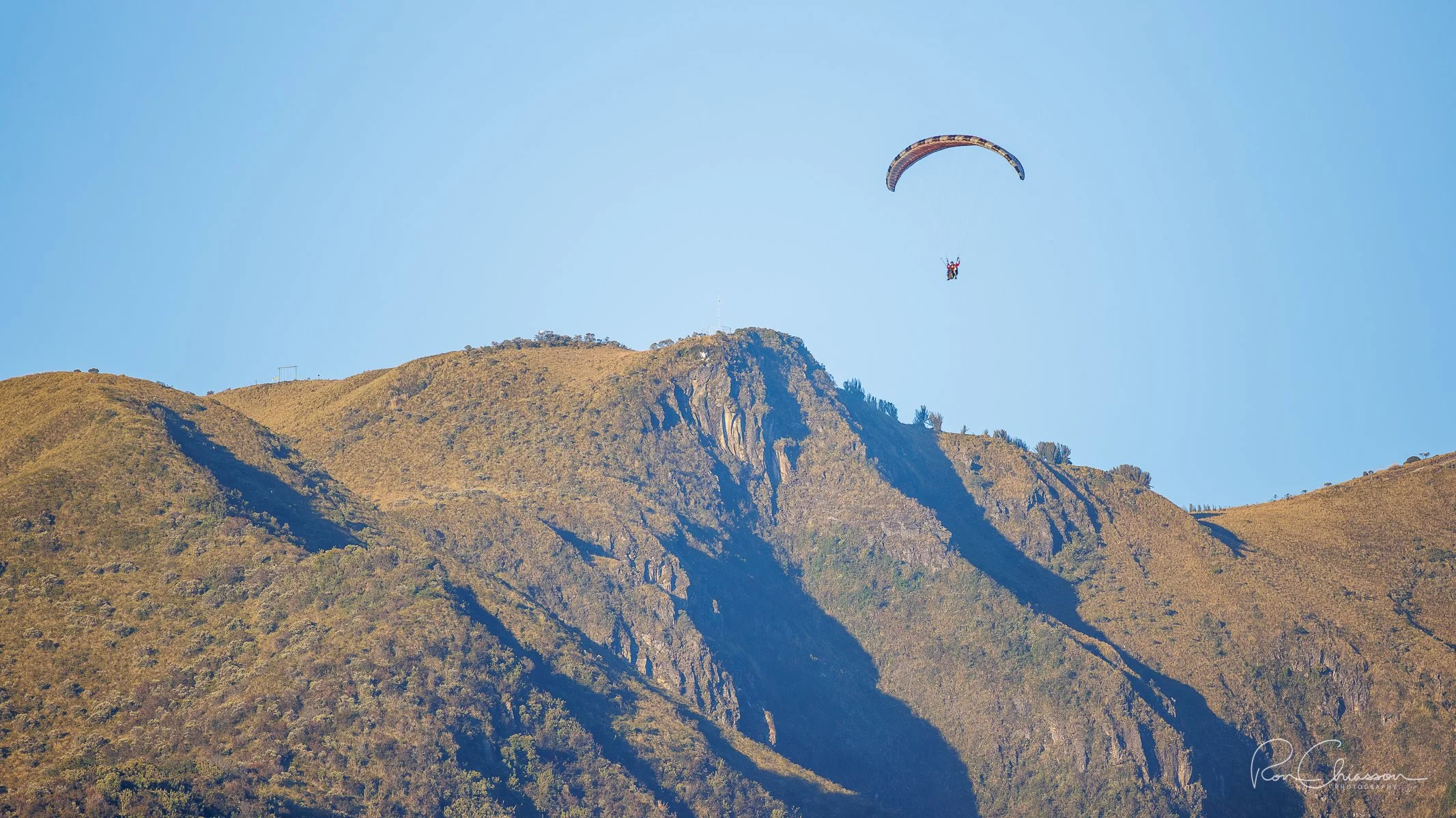 A paraglider is descending from Cruz Loma near the Teleferico in Quito.