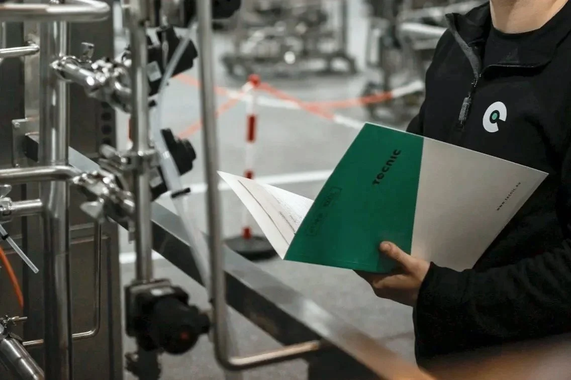 Person mit einer technischen Betriebsanleitung in einer industriellen Umgebung