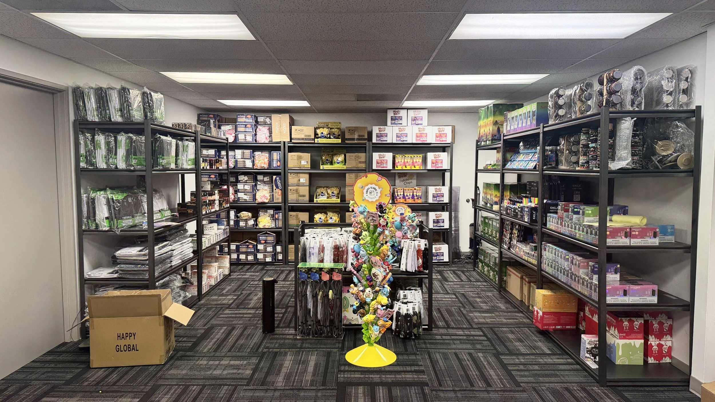 Store room with shelves filled with assorted hardware, tools, and supplies, and a cardboard box on the floor.