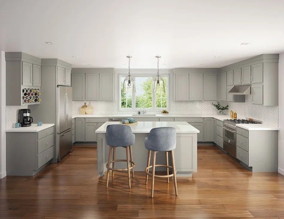 A modern kitchen with light gray cabinets, a white island, stainless steel appliances, and hardwood floors, with two gray bar stools at the island.
