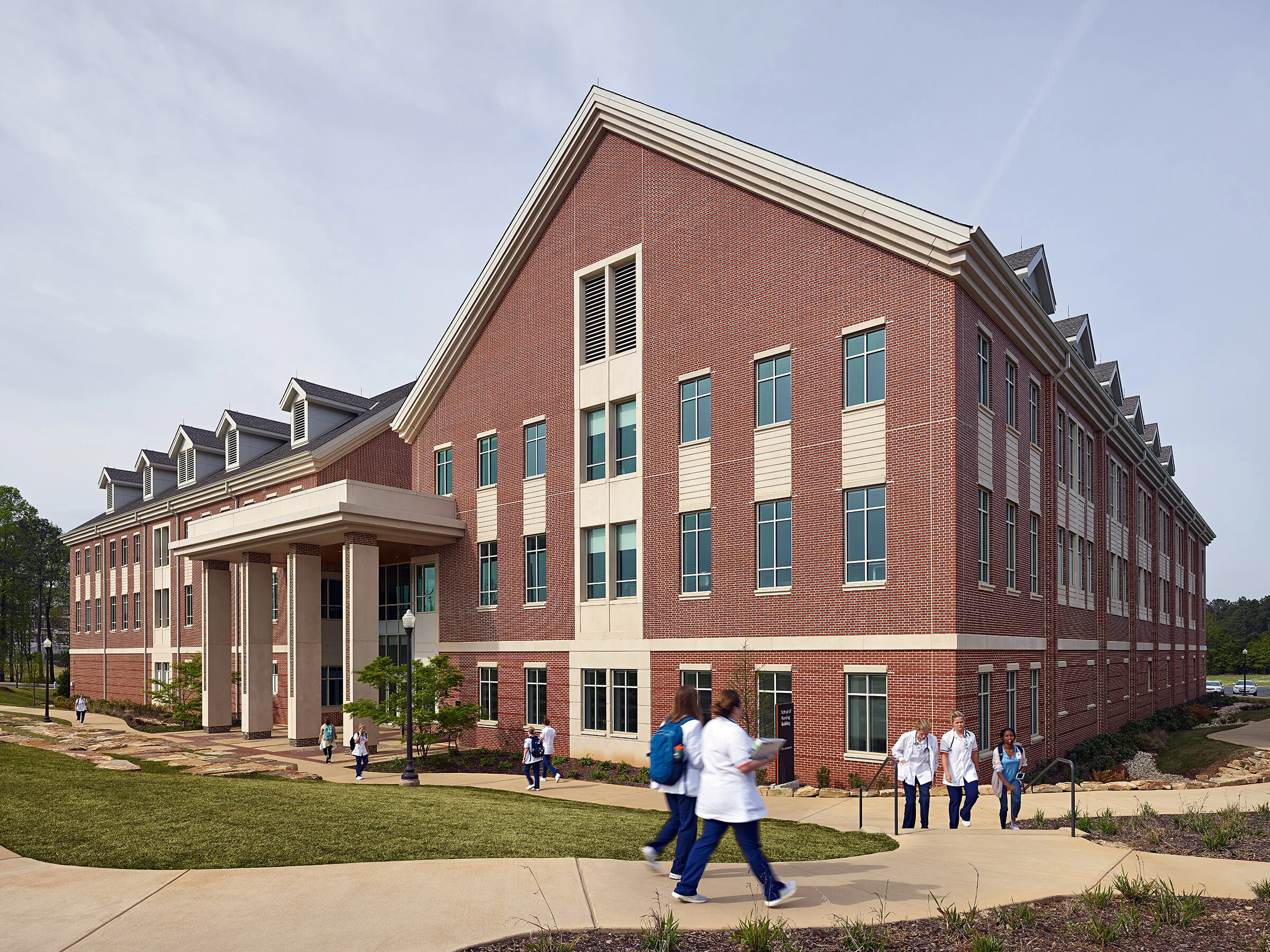 A large brick school building with students walking outside on a sunny day