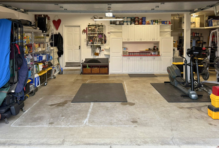 Garage with shelves, gym equipment, and storage cabinets.