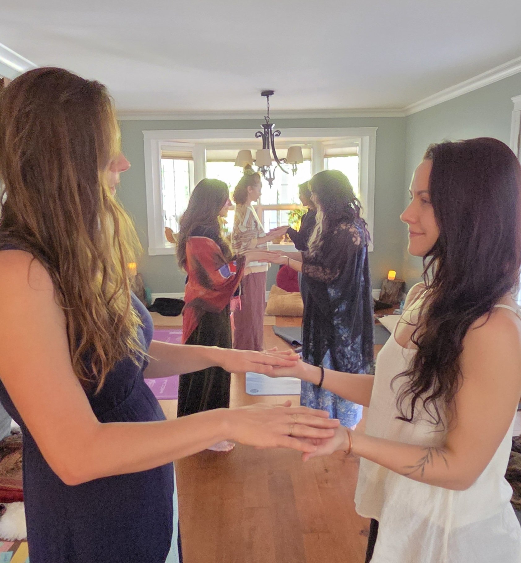 Group of women engaging in a meditation or mindfulness activity in a bright living room with soft lighting.