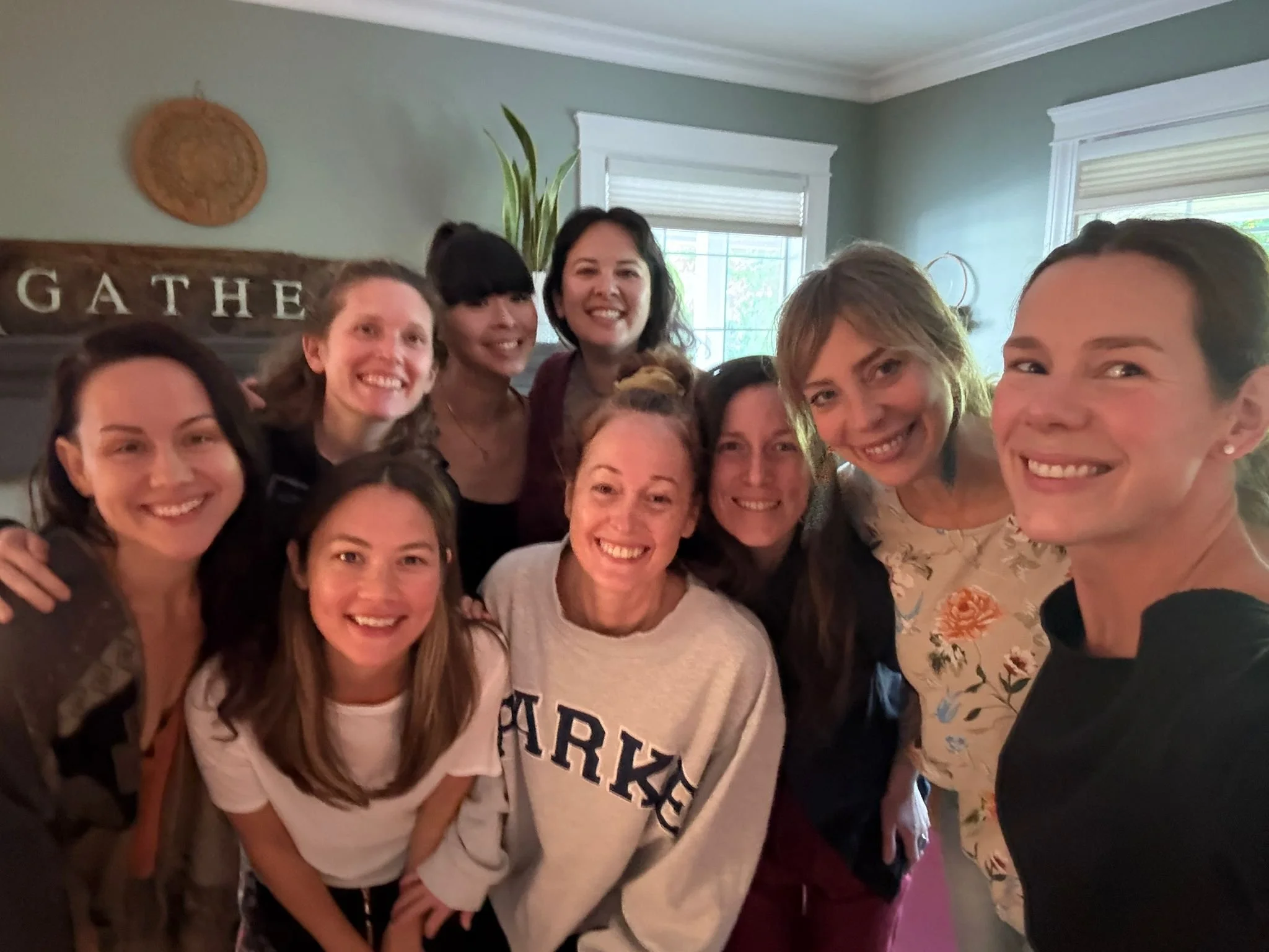 A group of women smiling and posing for a selfie indoors.