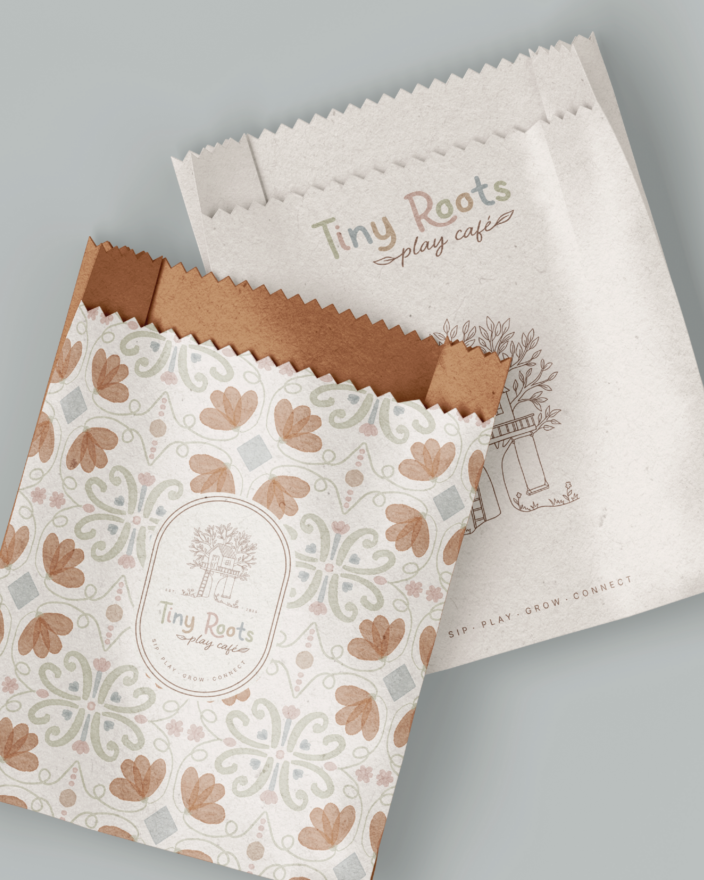 A printed paper bag and a paper shopping bag for Tiny Roots play cafe. The paper bag features a floral and butterfly pattern in earthy tones with the Tiny Roots logo at the center, while the shopping bag has the Tiny Roots logo and a line drawing of a treehouse.