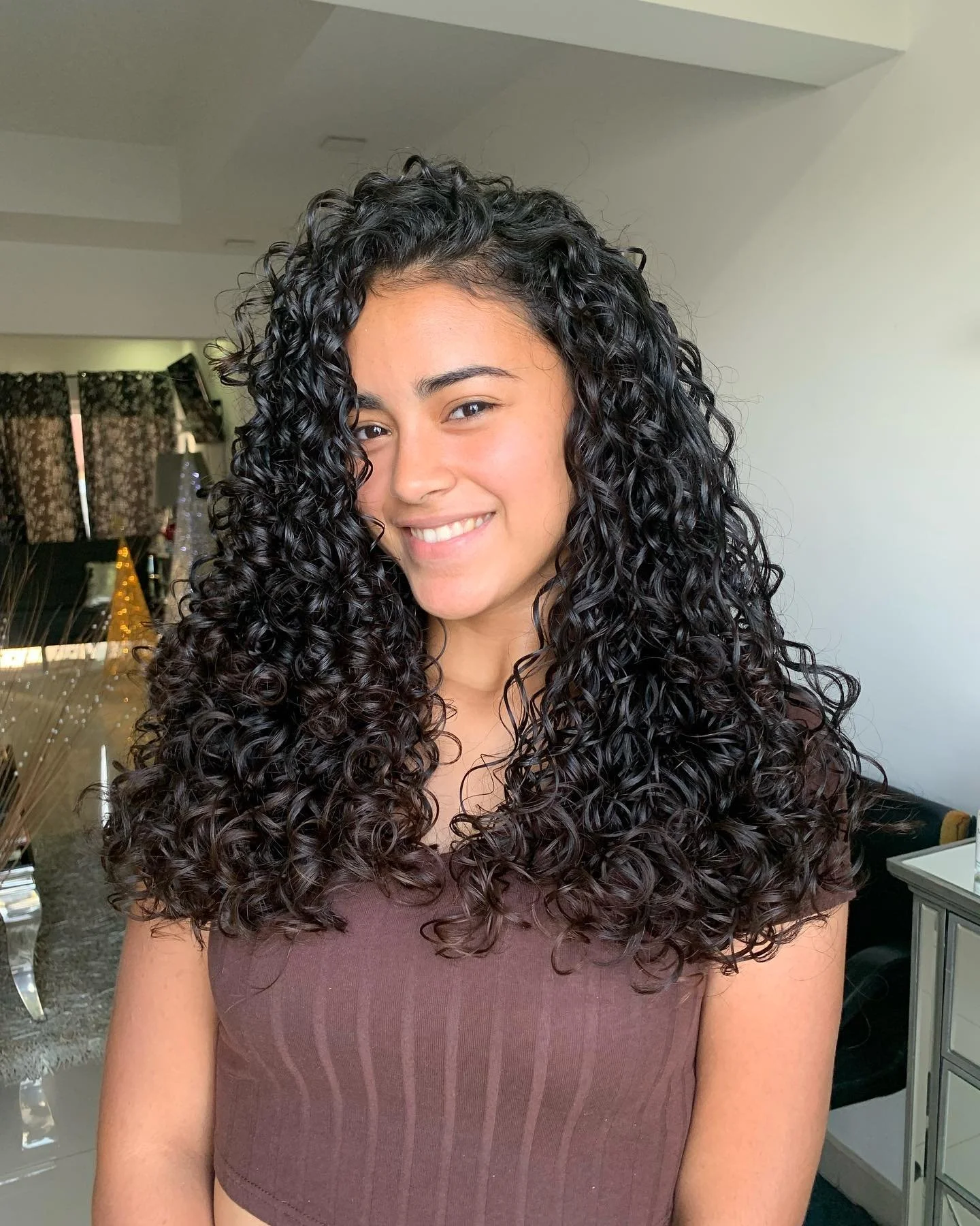 Young woman with long layers 3B curly black hair smiling  .