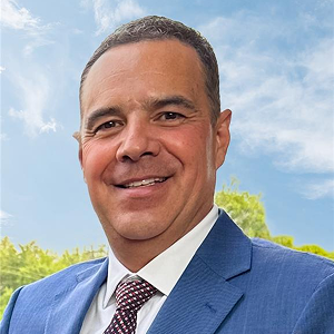 Lic. Alfredo López Muñoz, Secretario de Onexpo Nacional.
Hombre en traje azul y corbata, sonriendo, al aire libre con cielo y árboles de fondo.