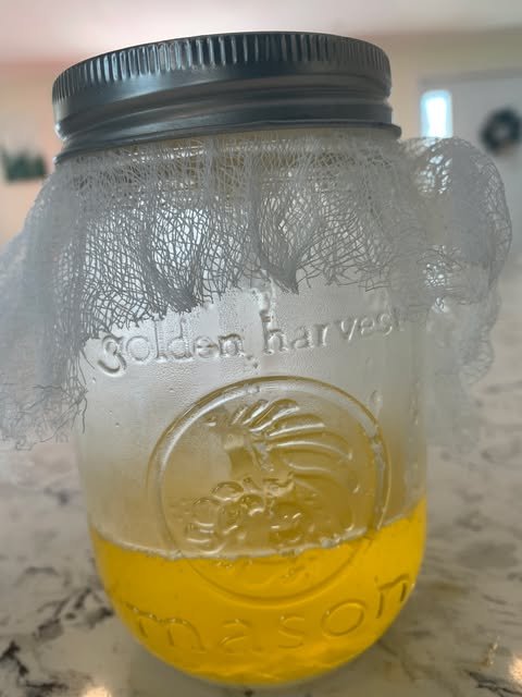 mason jar filled with clarified butter - ghee. The jar has embossed text that reads 'Golden Harvest.' Ayurveda's golden health liquid. Made at the homestead, classes to teach ayurvedic cooking. Old Roots Homestead. Ayurbeing personalized health.