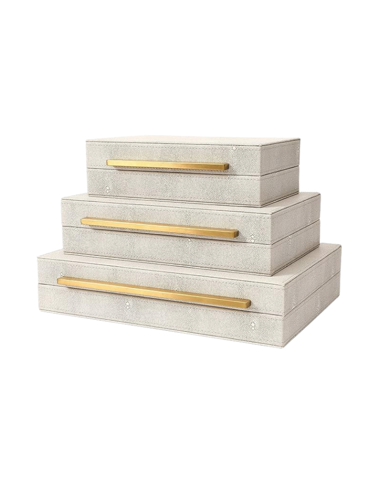 Three stacked white jewelry or storage boxes with gold handles.
