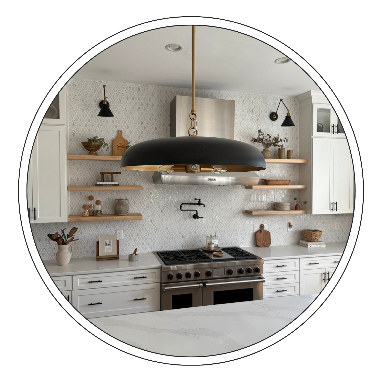 Modern kitchen with white cabinets, open wooden shelves, black wall sconces, a large black and gold pendant light, a stove with a mounted faucet, and decorative items like vases, bowls, and framed pictures.