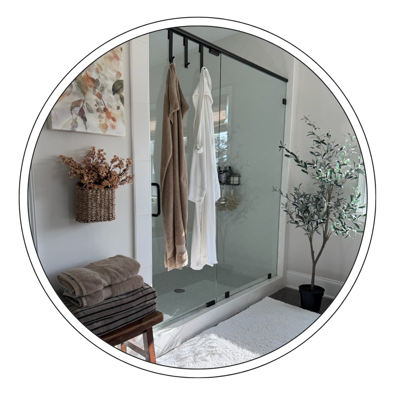 Bathroom with glass shower, hanging towels, indoor plant, wall art, baskets, towels, and floor rug
