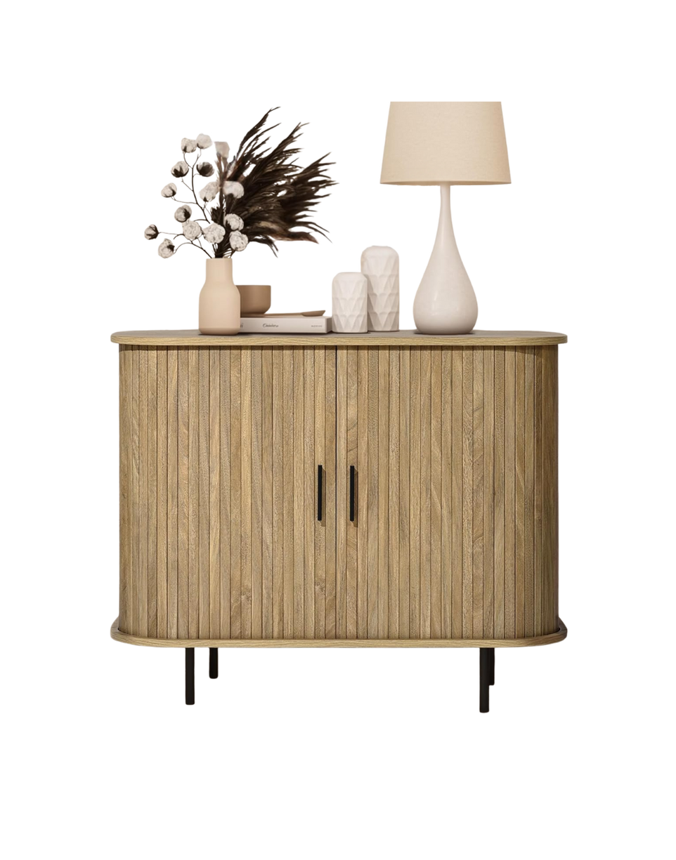 A wooden cabinet with two doors, decorated with a vase of dried flowers, two white vases, a table lamp, and some small decorative items on top.