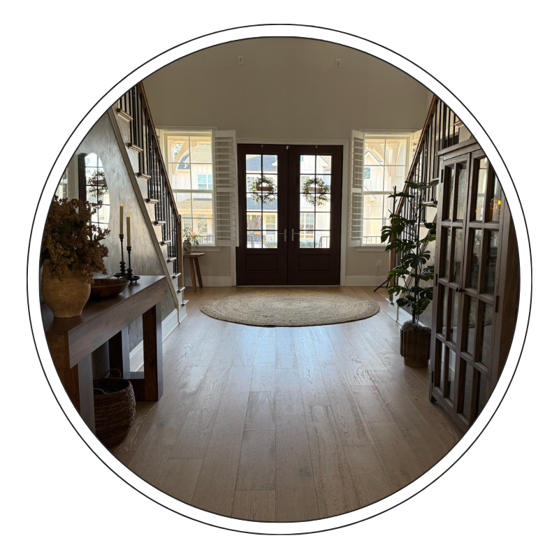 Entryway with front door, windows, a round rug, and decorative elements like plants and candles.