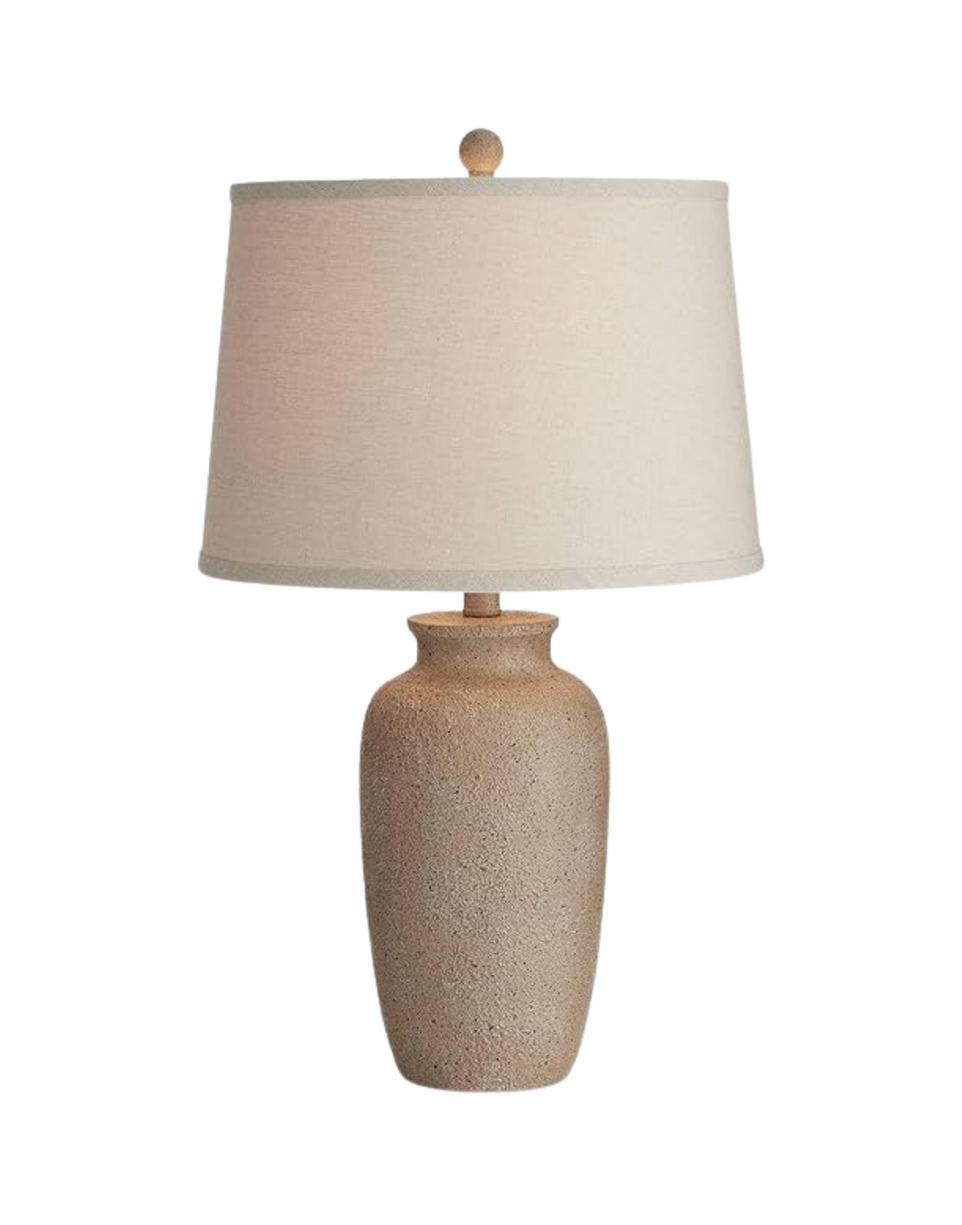 A beige table lamp with a textured ceramic base and a large off-white fabric lampshade.