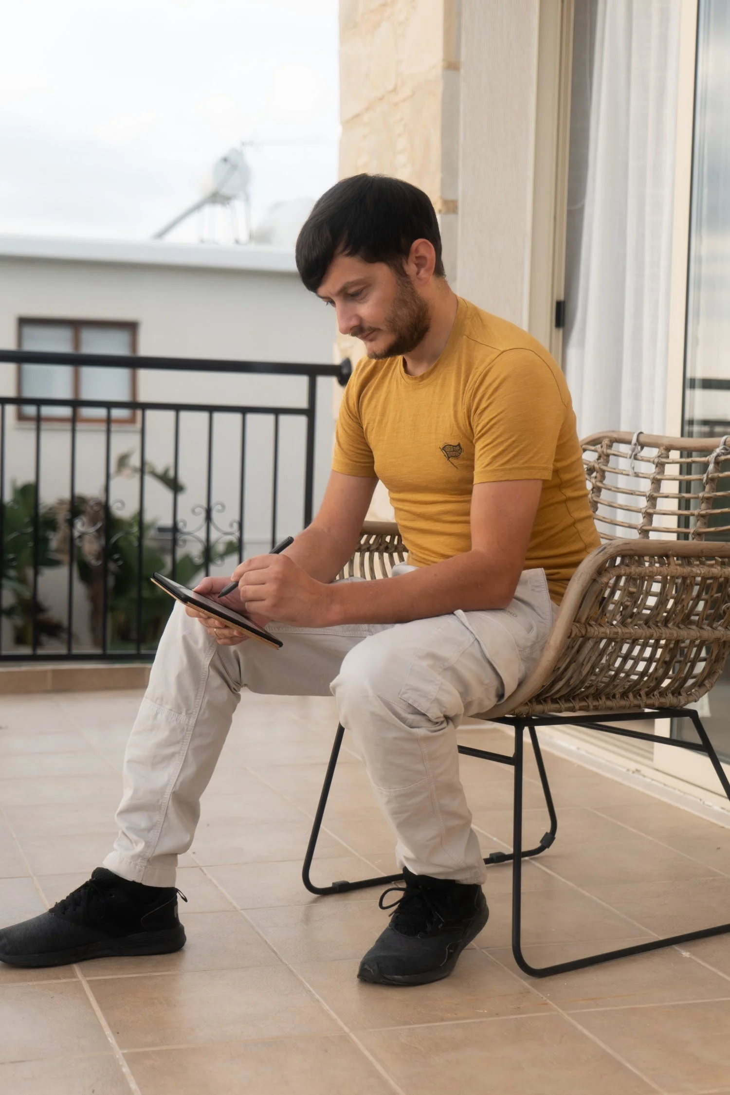 Jonathan sitzt auf einer Balkonterrasse und schreibt mit einem Ballpoint-Stift auf einem Tablett