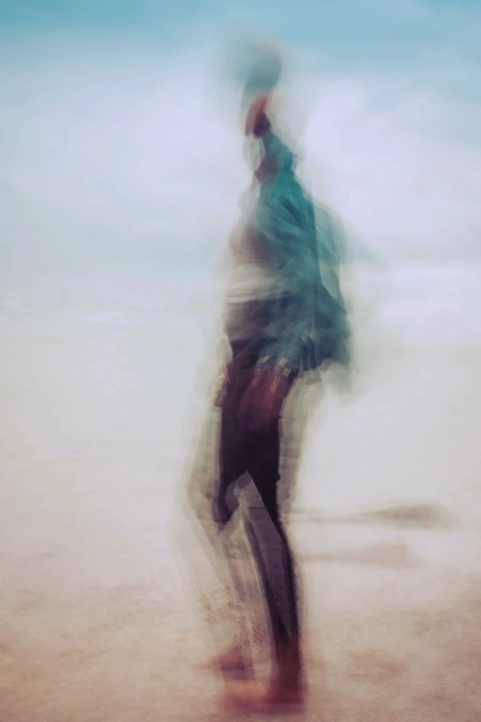 A blurry photo of a person standing and holding an umbrella in a foggy or misty outdoor setting.