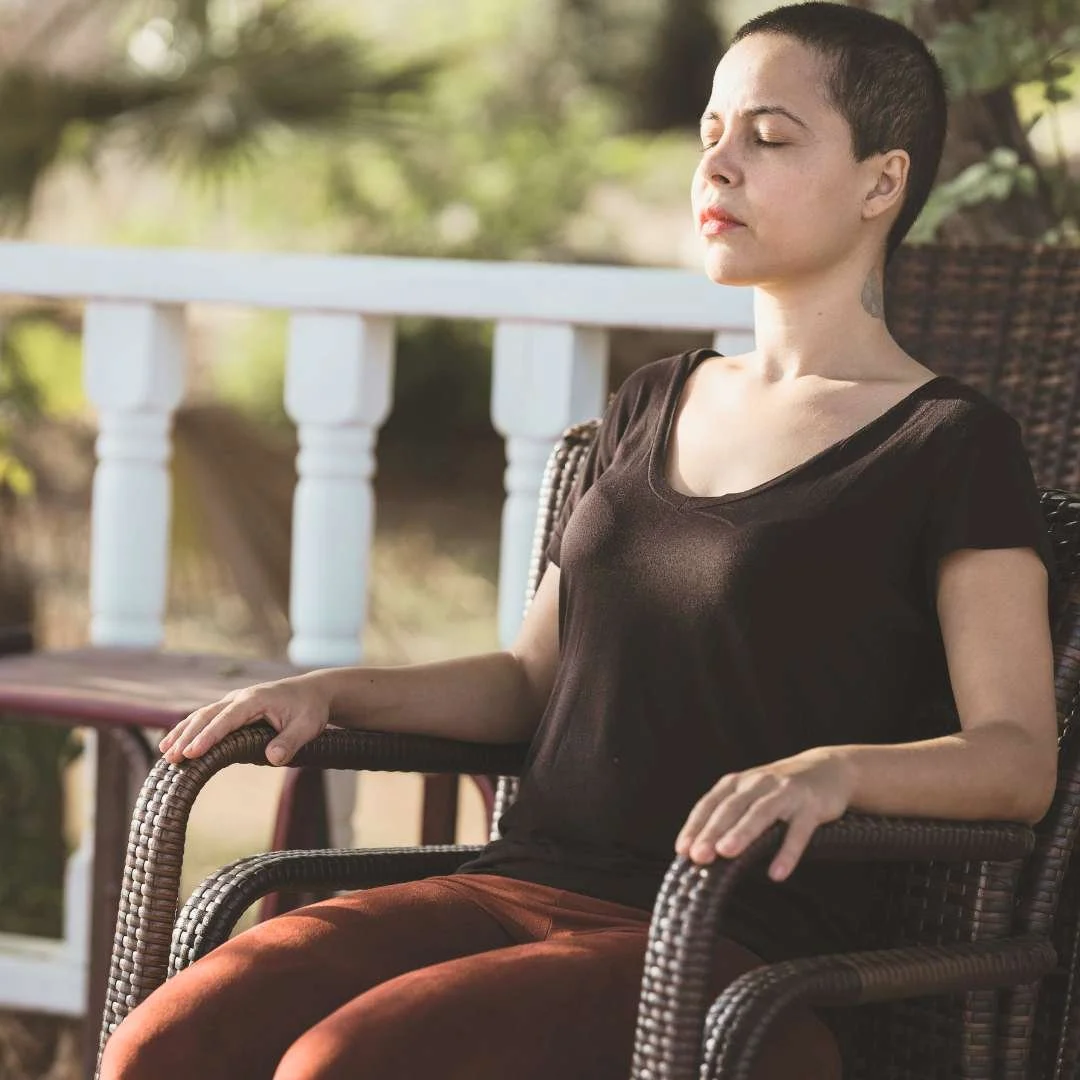 Person sitting quietly outdoors with eyes closed, embodying the calm and grounded state supported by 5NP ear acupuncture sessions with Mel Rolfes.