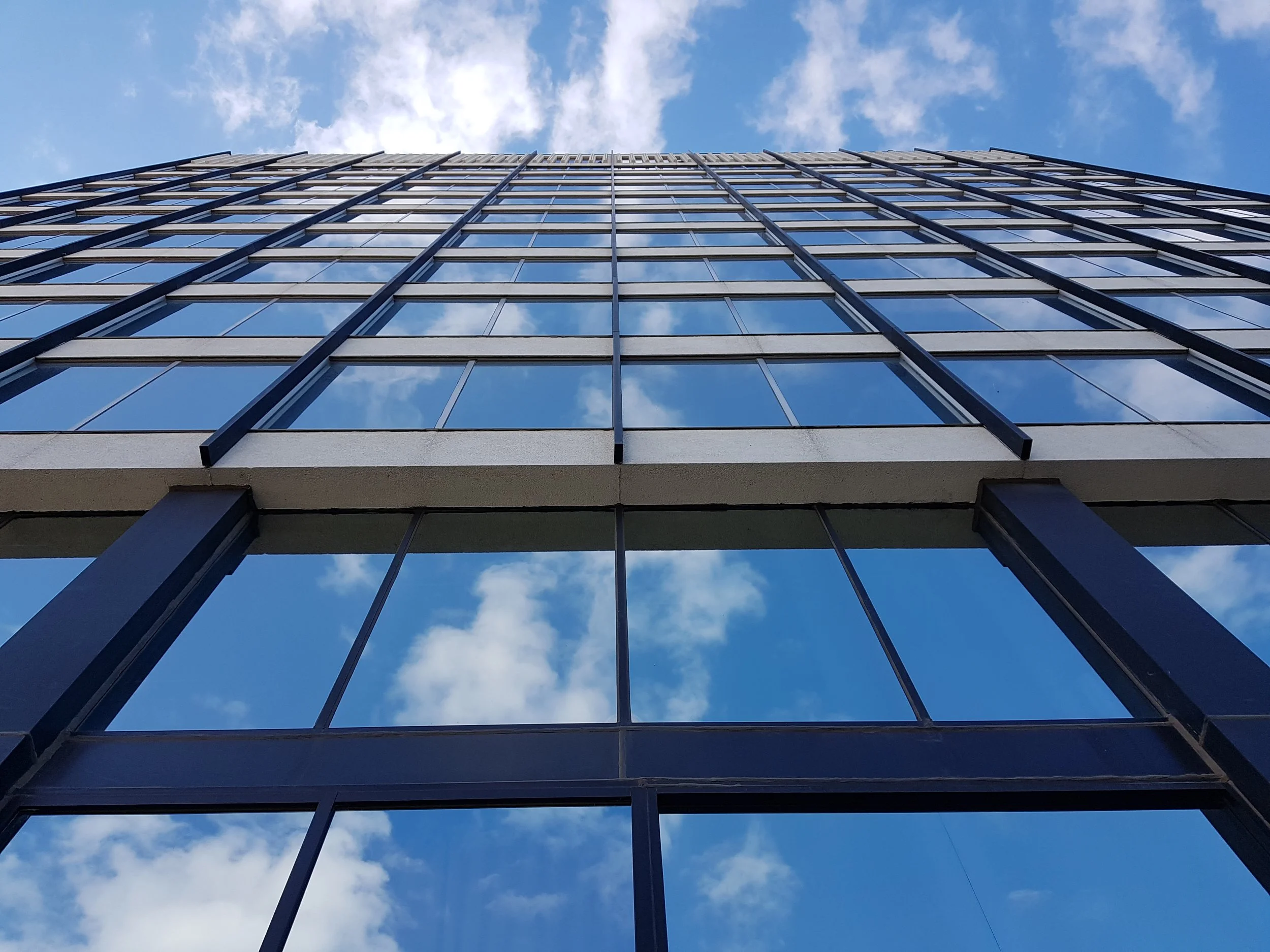 Clouds and a blue sky reflecting off the windows of an office building