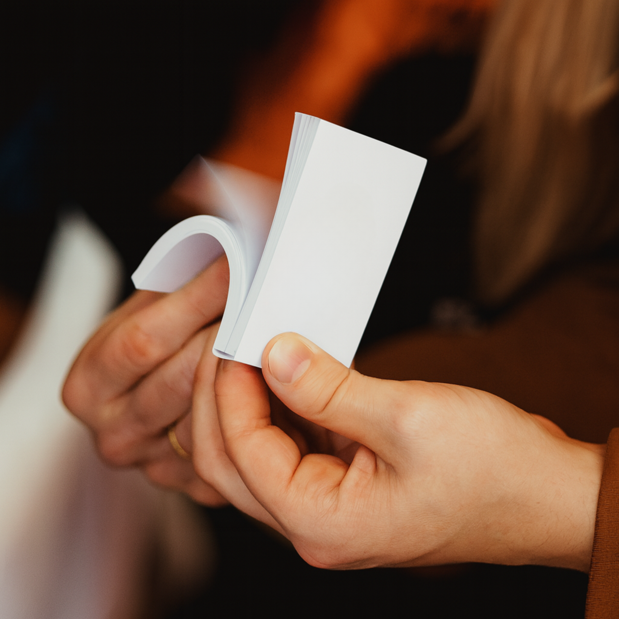 A person holding a blank, white, folded paper note card in their hand.