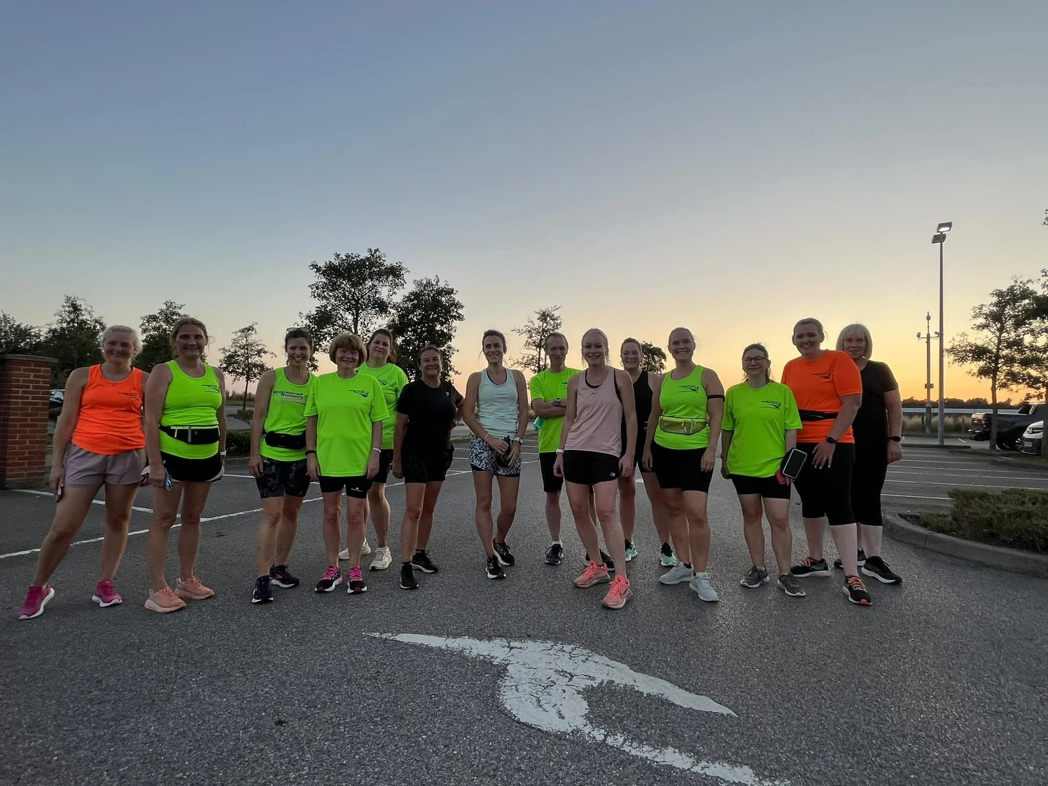 Group of B2R members in athletic clothing standing together outdoors at sunset.