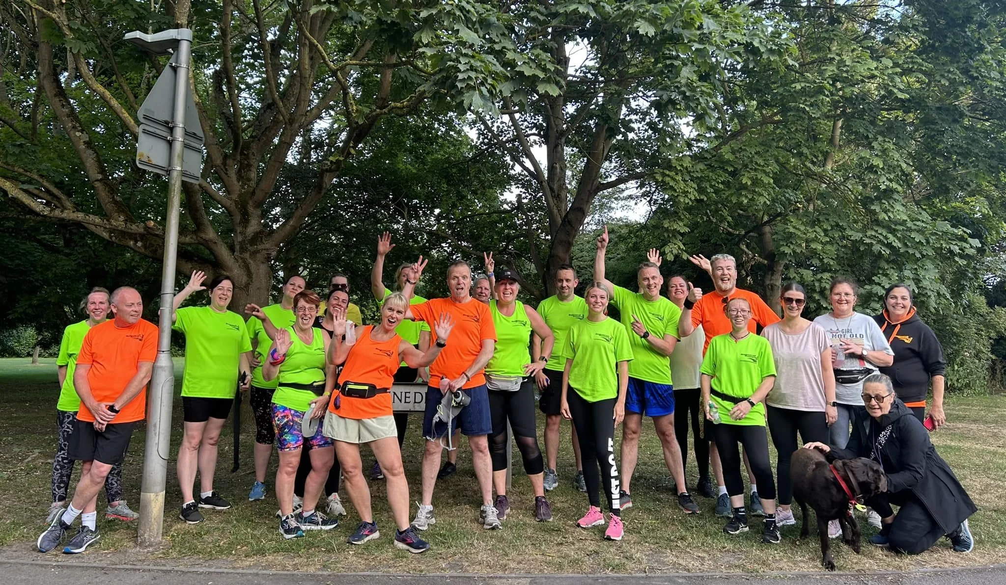 Group of B2R members in colorful athletic clothing smiling and posing outdoors in a park with trees in the background.