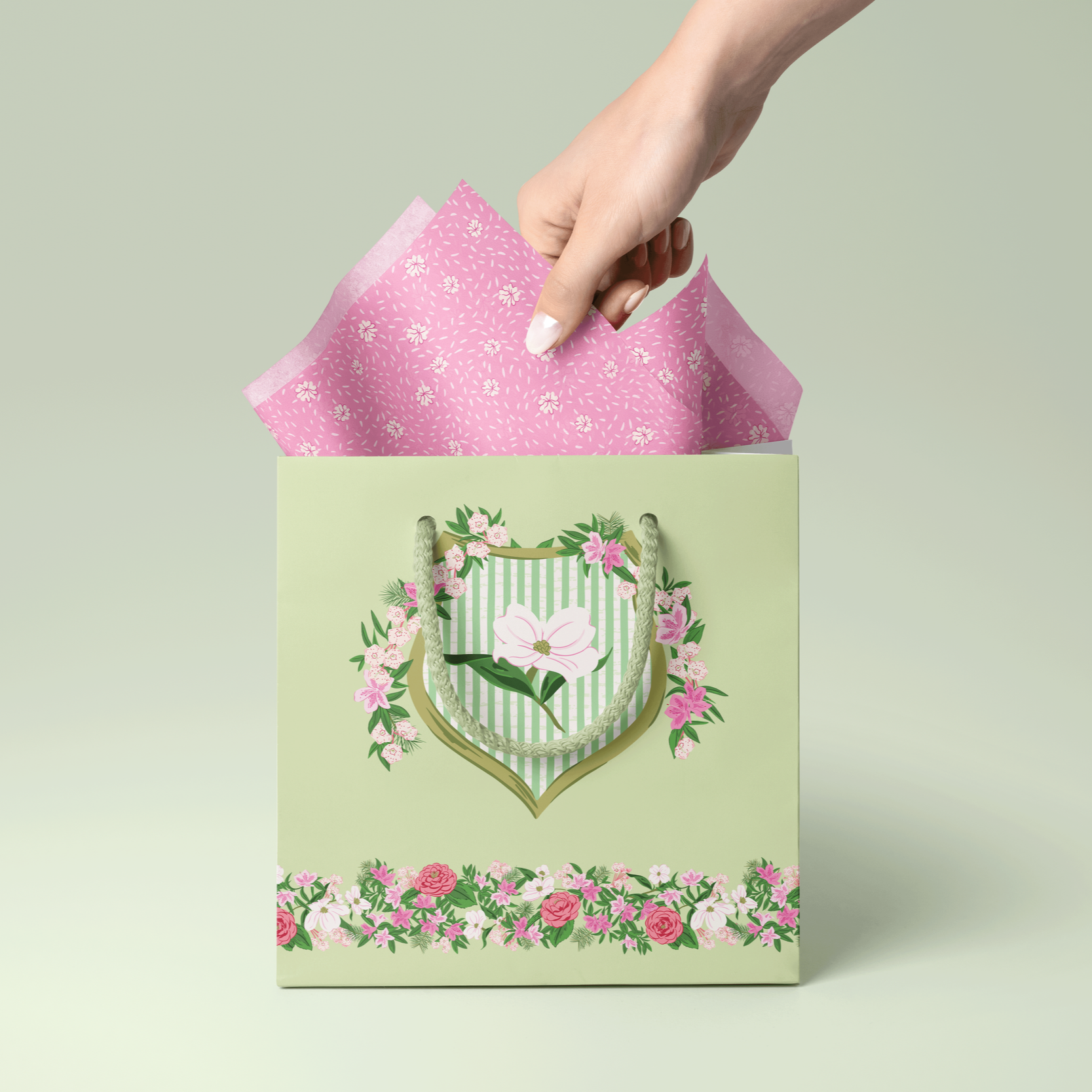 Gift bag featuring the League Crest illustration and floral border detail, filled with coordinating pink patterned tissue paper.