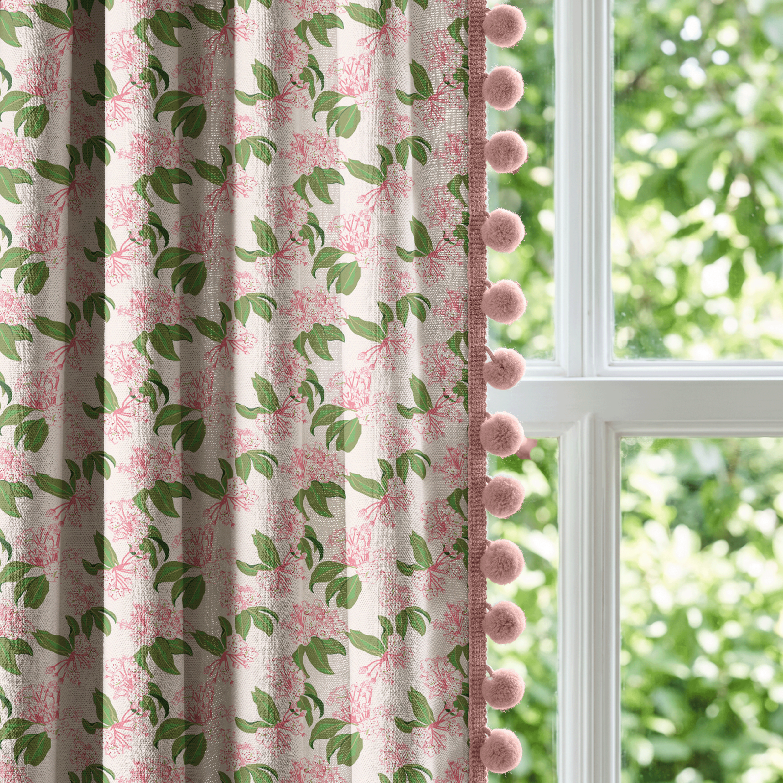 Mountain Laurel Charm floral fabric displayed as decorative curtains with pom-pom trim beside a sunlit window.