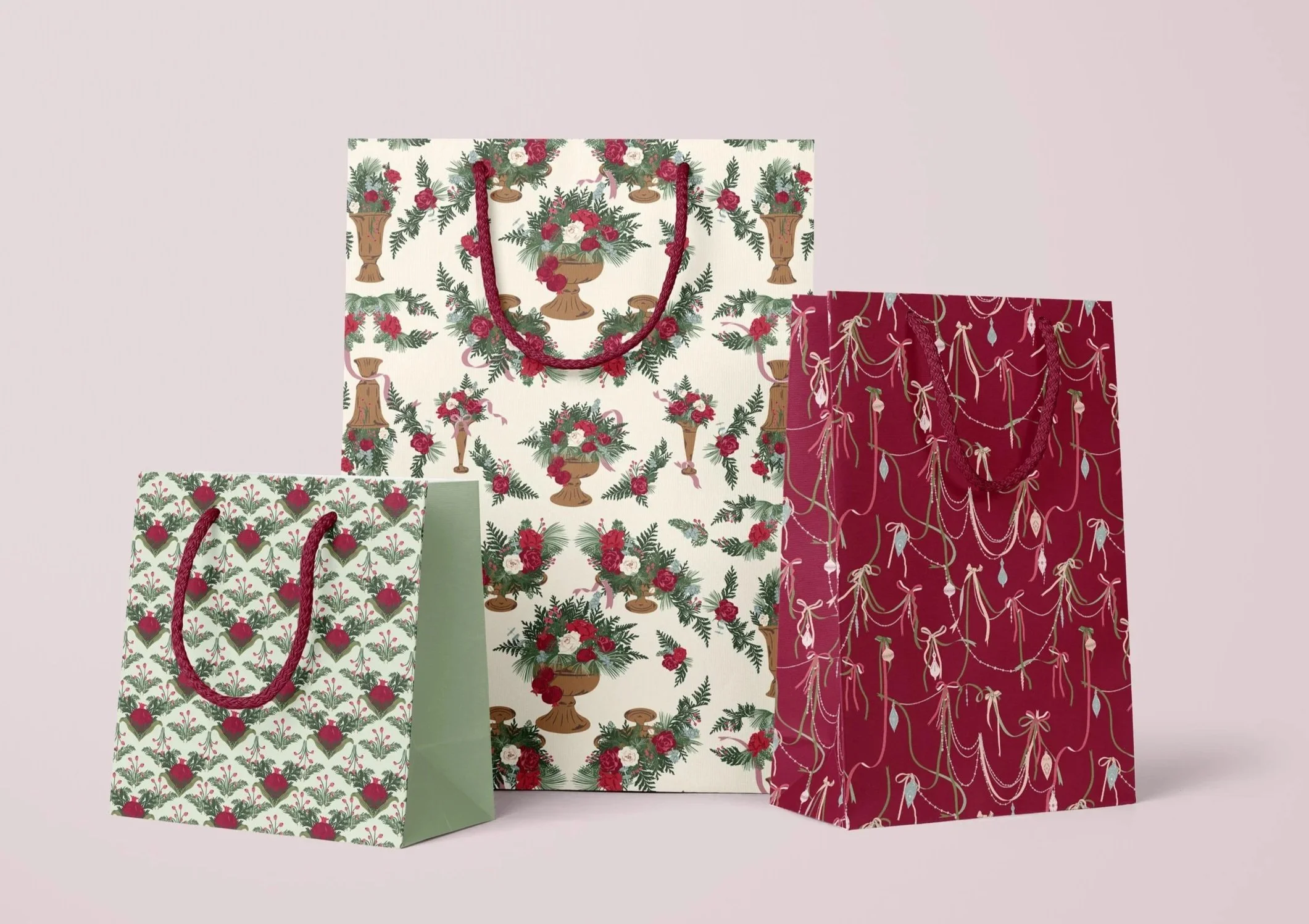 Coordinating holiday gift bags featuring stylized pomegranates, elegant winter floral arrangements, and draped ribbon garlands.