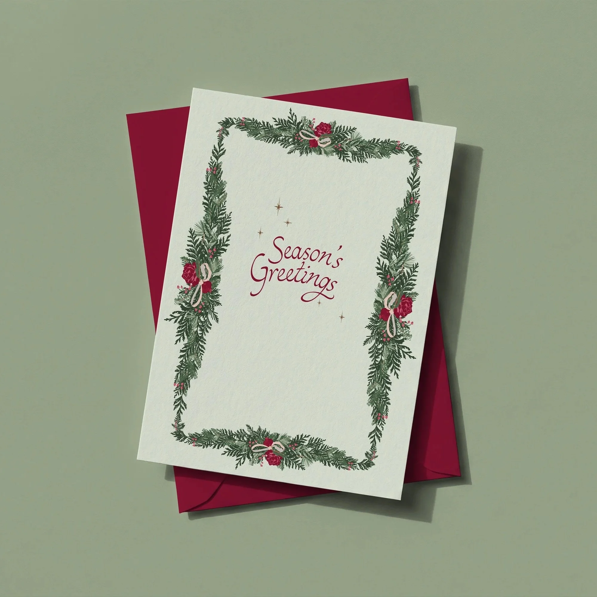 Holiday greeting card featuring an evergreen garland border framing the message "Season's Greetings," paired with a coordinating burgundy envelope.