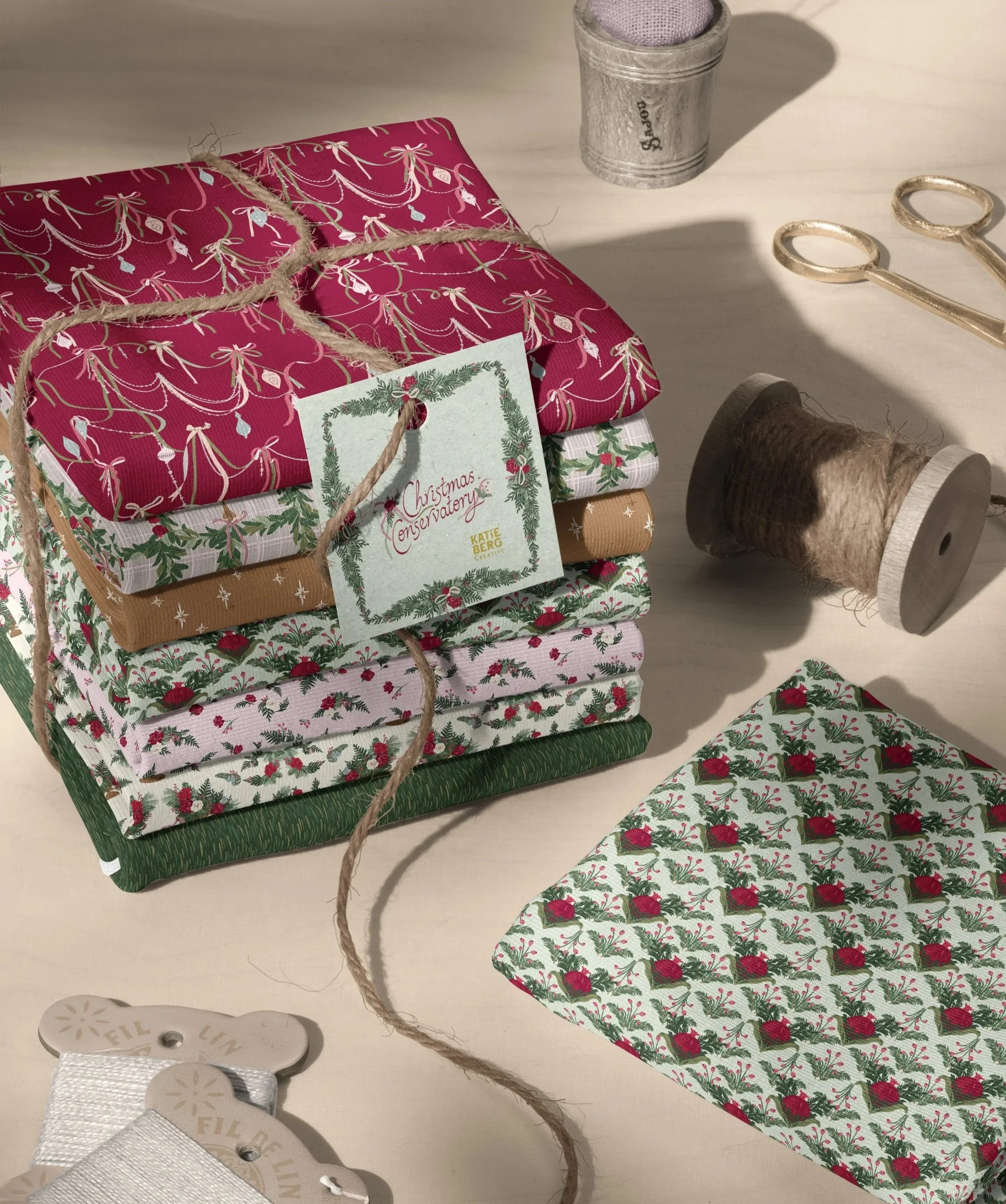 Three hanging Christmas stockings featuring coordinating holiday prints: draped ribbon garlands on cranberry, scattered winter florals on blush pink, and stylized pomegranate motifs framed by evergreen sprigs.